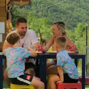 Familia sentada en la terraza de bar con vistas a la naturaleza.